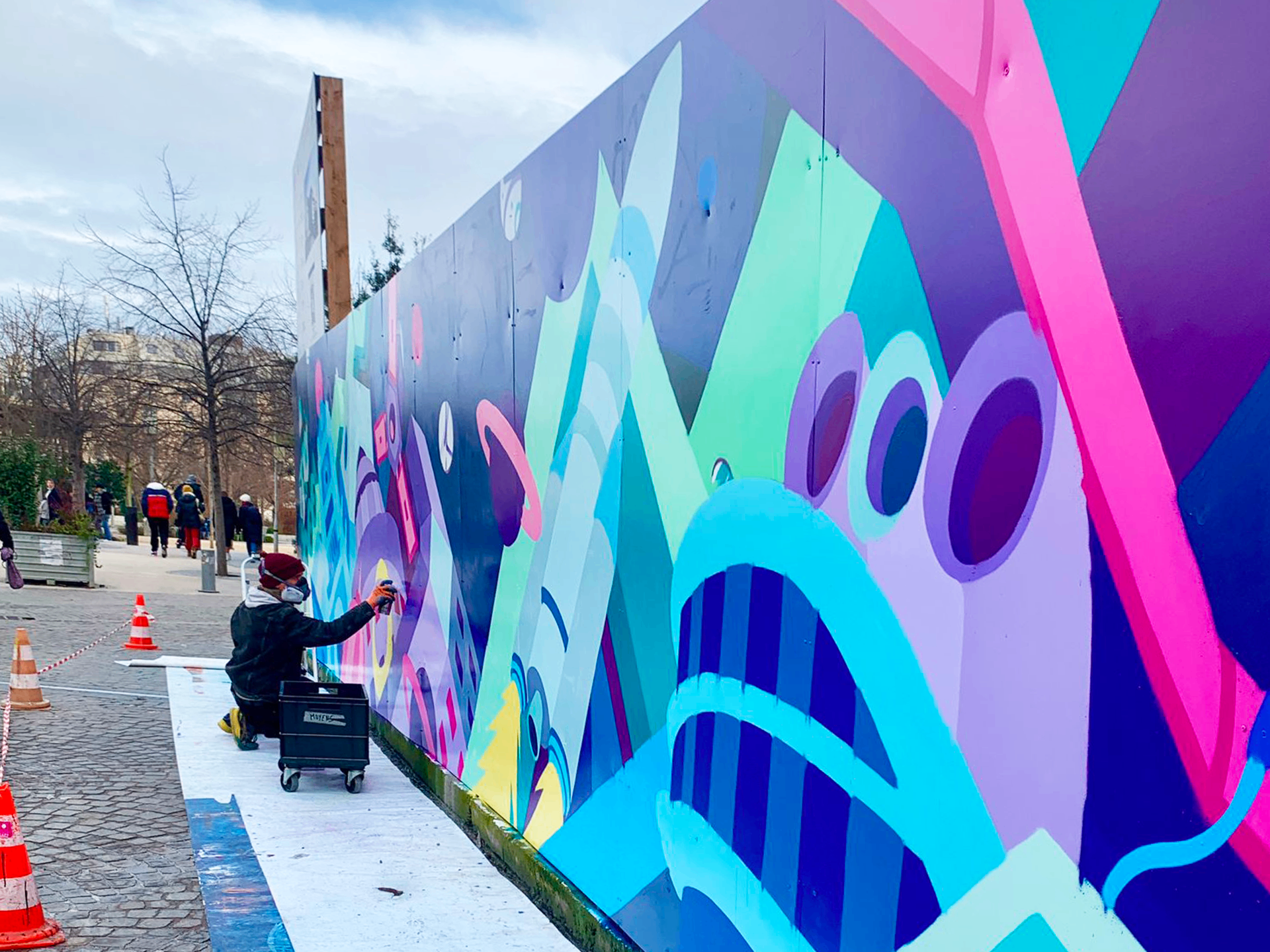 Meyso à la bombe aérosol devant la fresque colorée