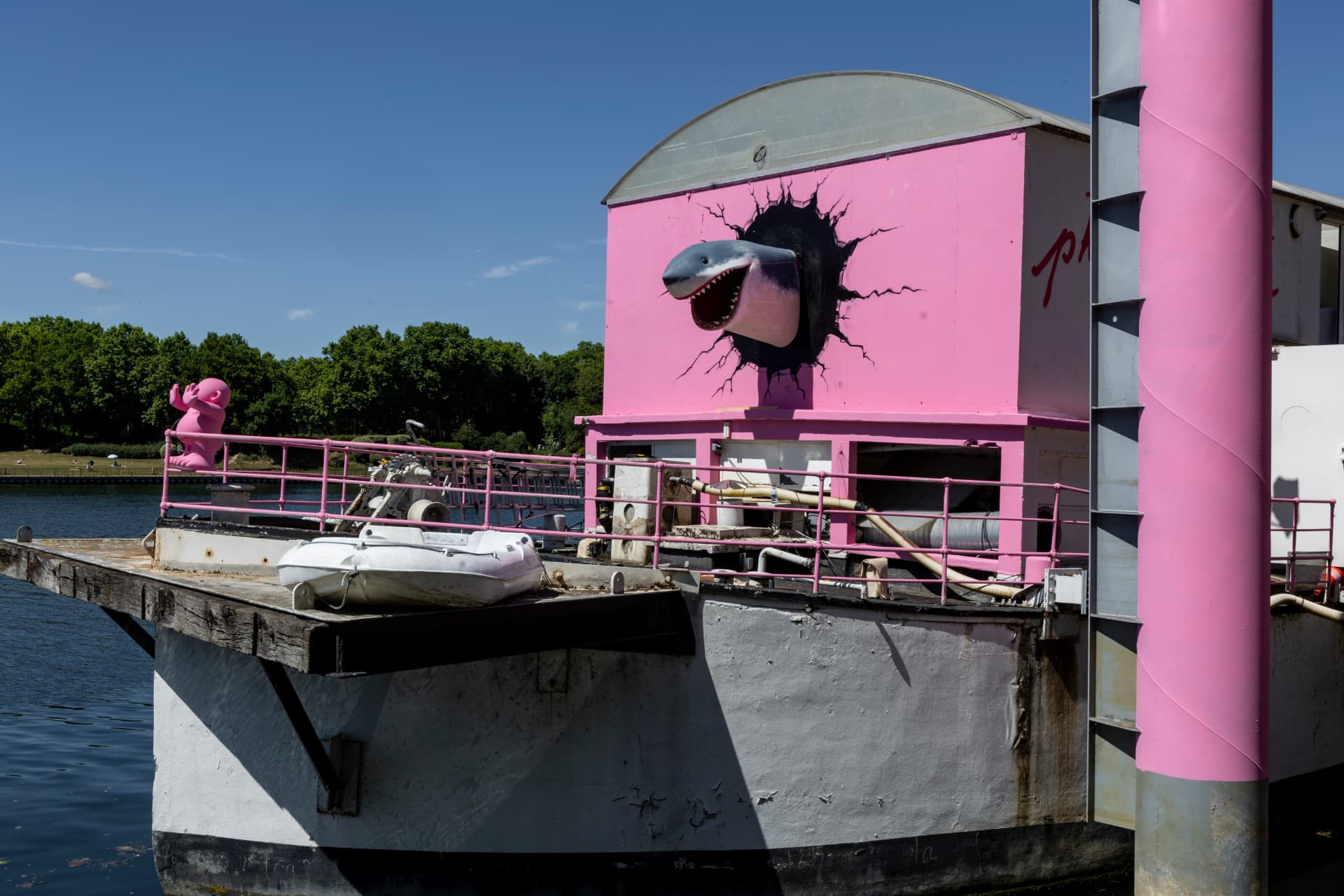 Façade rose de la péniche Touta avec la sculpture de requin