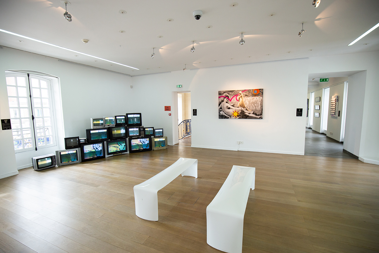Salle d'exposition avec installation vidéo et œuvre street art