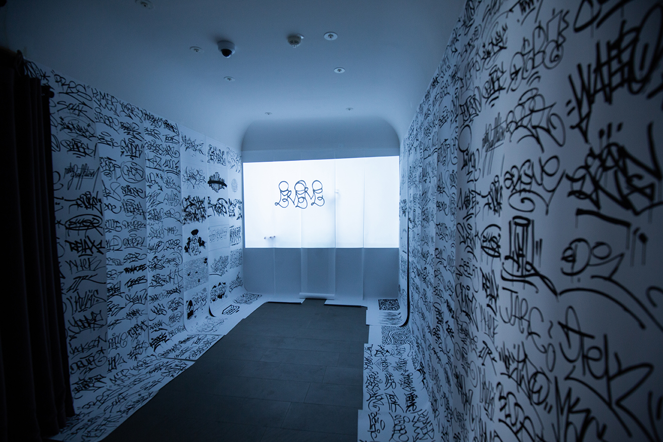 Couloir immersif tapissé de graffitis noirs et blancs